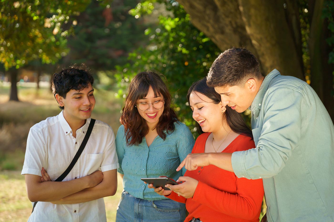 A group of students study information on a tablet during a campus tour.