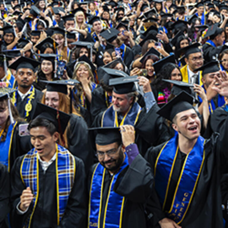 Students in caps and gowns move their tassels as part of the commencement ceremony